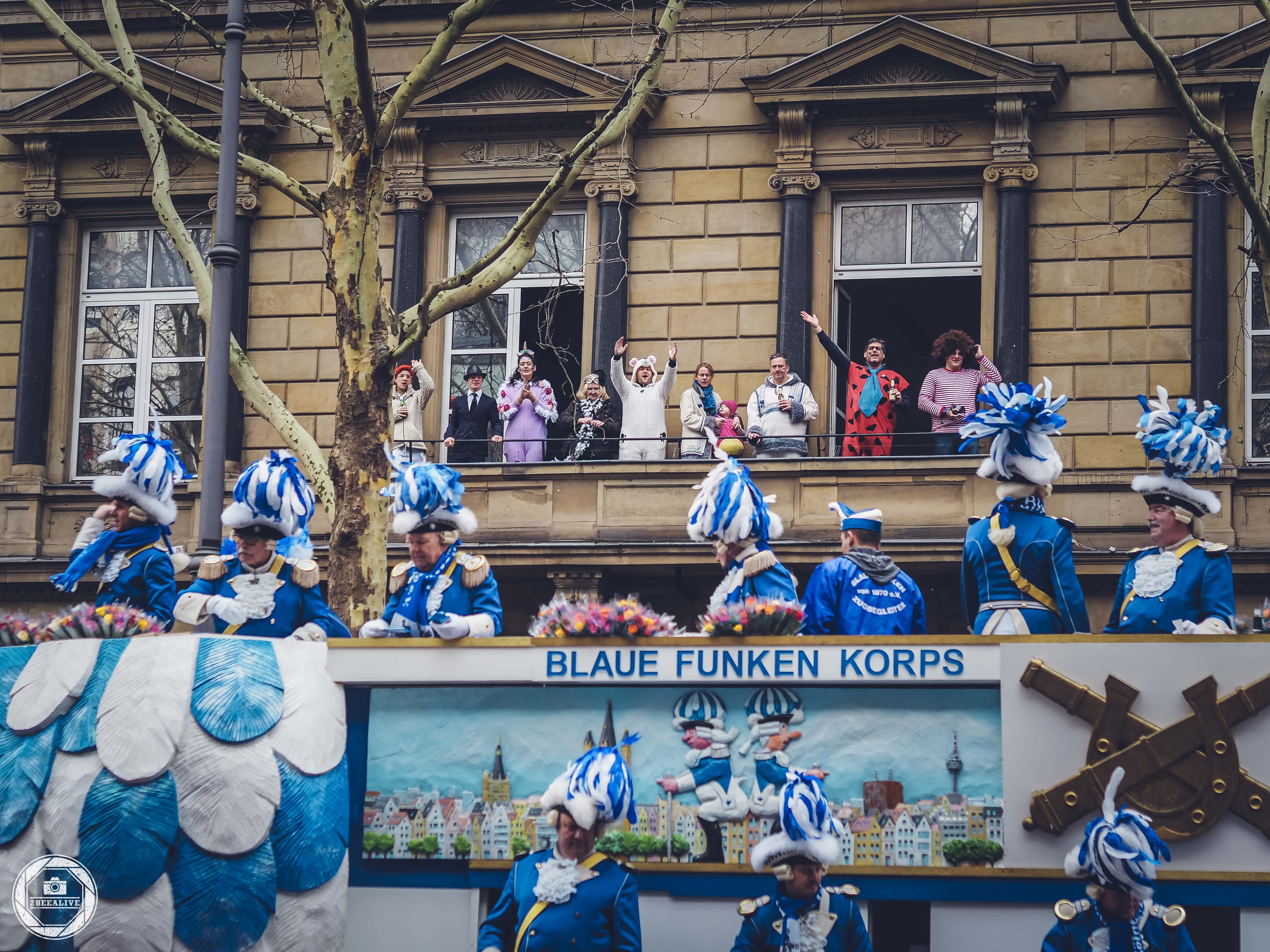 Jecke jubeln Blauen Funken beim Kölner Rosenmontagszug 2019 vom Balkon aus zu